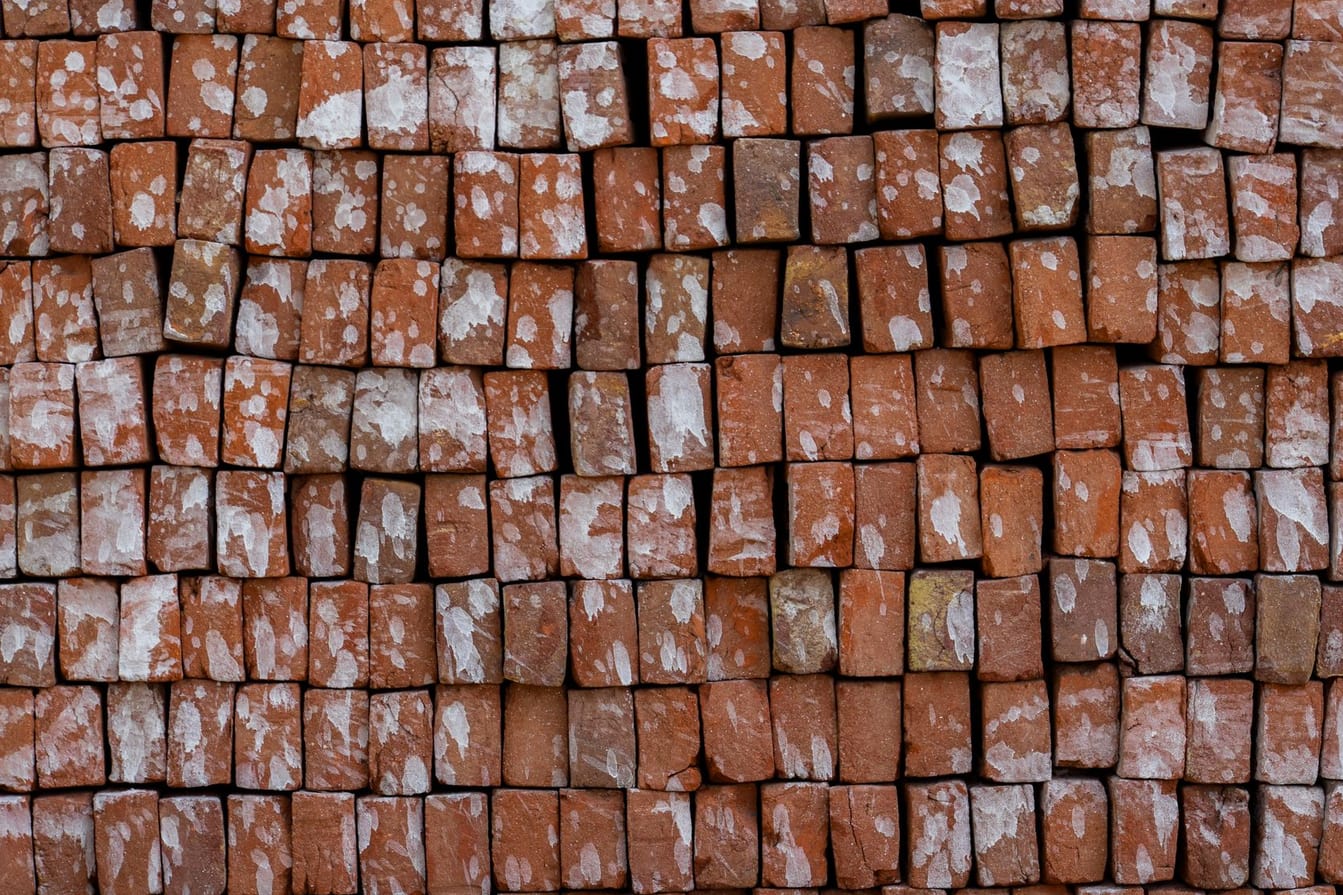 Stacks of fired red clay bricks in a ceramic production yard